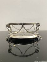 Front view of circular silver-plated cellar with chain garlands and hoof feet