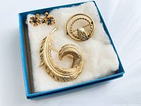 Entire lot in box showing feather brooch, pearl circle brooch and flower earrings