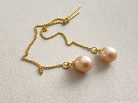 Pair of pearl threader earrings laid flat showing pearls and gold-tone chains