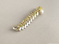 Full view of hair clip showing gold plating, rhinestones, pearl