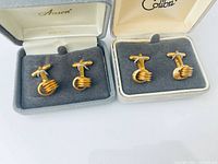 Both pairs of gold-plated knot cufflinks in their respective Anson and Colibri boxes