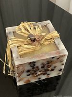 Front view of square candle showing embedded botanicals