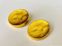 Front view of both oval gold tone earrings showing brushed texture