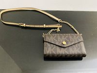 Full view of Michael Kors monogram crossbody with strap attached