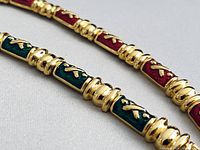 Close-up of green and red enamel X-link sections showing gold-tone finish