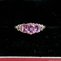 Front view of white gold ring showing three pink sapphires and diamond shoulders