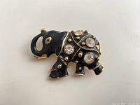 Front view of black enamel elephant brooch showing rhinestone placement and gold detailing