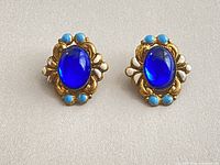 Front view showing cobalt blue cabochon centers and enamel accents on both earrings