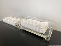 Two clear lucite tissue holders side by side filled with tissues