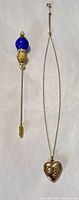 Locket necklace and stick pin displayed side by side