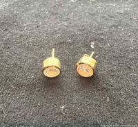 Pair of 14K gold stud earrings front view on fabric background