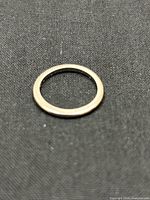 Full view of thin 18K gold band ring on dark fabric