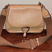 Front view of camel pebbled leather bag with wide fabric strap attached