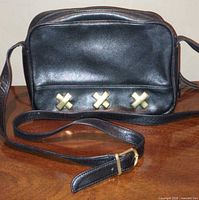 Front view of black leather bag with gold X accents and adjustable strap