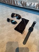 Lot overview showing smartwatch, two sunglasses, pouch