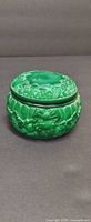 Front view of bright green molded glass trinket jar with lid