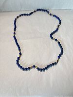 Full view of single-strand lapis lazuli bead necklace laid flat