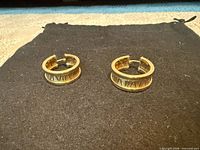 Front view of both gold huggie hoop earrings on black cloth