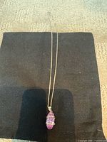 Full view of necklace laid flat on dark cloth showing chain length and pendant