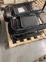 Stack of black metal folding chairs on pallet