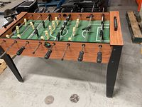 Perspective view of the entire foosball table showing cabinet, playfield, rods, players and legs