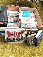Overall view of two boxes filled with assorted DVDs and D-Day books