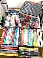 Overhead view of two boxes of assorted DVDs and VHS, titles visible