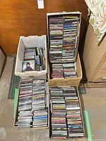 Three boxes and one tote filled with rows of CDs in jewel cases