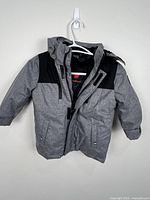 Front view of grey and black Canadiana winter coat hanging on hanger