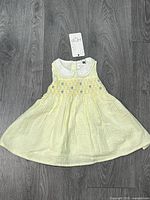 Full view of yellow and white striped sleeveless dress on floor