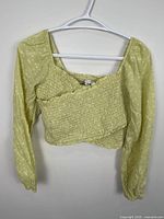 Front view of green floral cropped wrap top on hanger