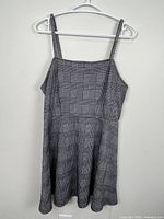 Front view of black and white houndstooth long top on hanger