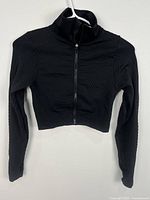 Front view of black textured cropped jacket hanging