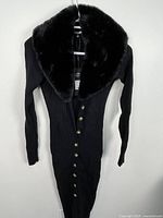 Full view of black ribbed midi dress with gold buttons and faux fur collar