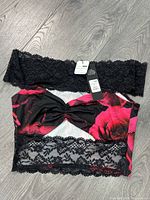 Front view of black lace and red rose print crop top with tag