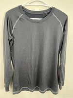 Front view of grey long sleeve athletic top on hanger