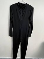 Full view of black long-sleeve jumpsuit hanging