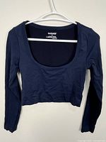 Front view of navy blue long sleeve cropped top on hanger