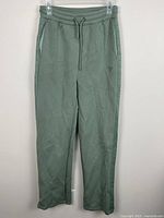 Full front view of sage green Guess sweatpants hanging
