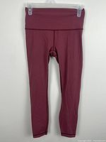 Front view of burgundy Lululemon leggings on hanger