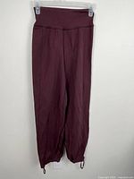 Front view of burgundy Lululemon yoga pants on hanger