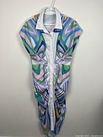Full view of sleeveless psychedelic button-down dress on hanger