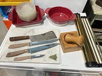 overall lot showing knives, marble board, mortar & pestle, red bakeware, plastic bowls