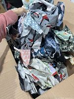 Open cardboard box filled with mixed fabric scraps