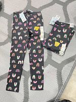 Two stacks of Cat & Jack rainbow leggings showing full length view and tags attached