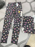 Full view of one pair of leggings laid flat and stacked remaining pairs beside it