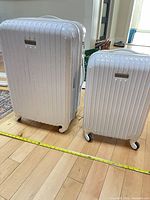 Both Champs white hardshell suitcases side by side showing size difference and spinner wheels
