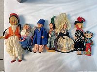 Seven vintage dolls laid out side by side