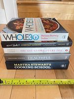 Stacked side view of all five cookbooks with tape measure for scale