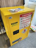 Front view of yellow fireproof cabinet showing warning labels and lock